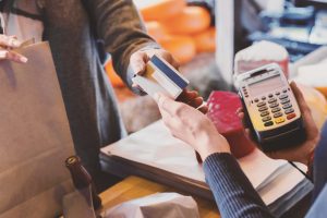 Cashless payment. Hand of customer giving credit card to store cashier at checkout, panorama