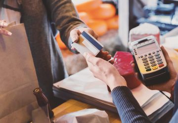 Cashless payment. Hand of customer giving credit card to store cashier at checkout, panorama