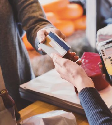 Cashless payment. Hand of customer giving credit card to store cashier at checkout, panorama