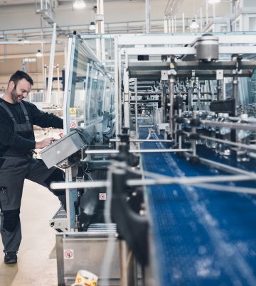 Happy smiled worker doing his job on Robotic factory line for pr