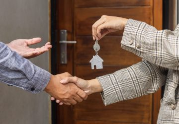 Real estate agent handing over the house keys in front of a new