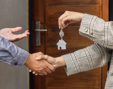 Real estate agent handing over the house keys in front of a new