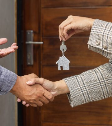 Real estate agent handing over the house keys in front of a new